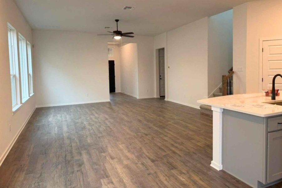 Unfurnished living room featuring dark wood-style floors and a ceiling fan