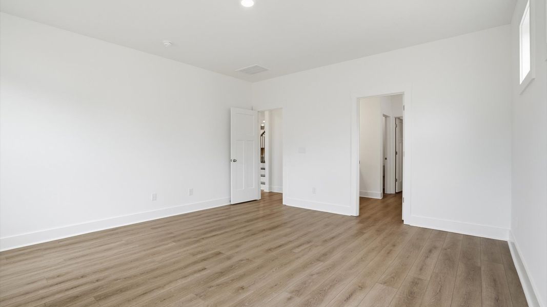 Elegant primary suite with hardwood flooring and superior natural light in this accomplished DRB Homes design