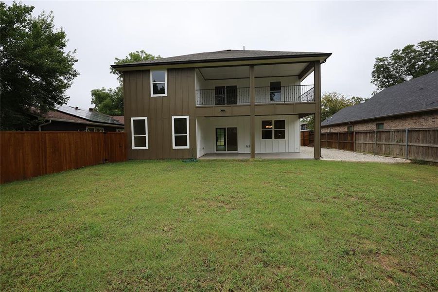 Back of property featuring a patio area, a fenced backyard, board and batten siding, and a balcony