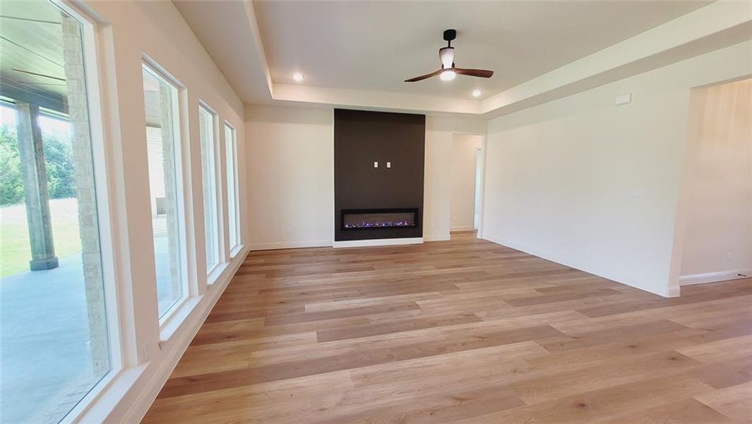 Spacious interior featuring wood-finish flooring, a contemporary fireplace, multiple windows, recessed lighting, and a ceiling fan