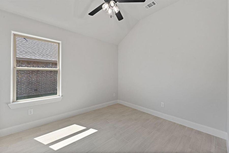 Spare room featuring lofted ceiling, a ceiling fan, and light wood-type flooring