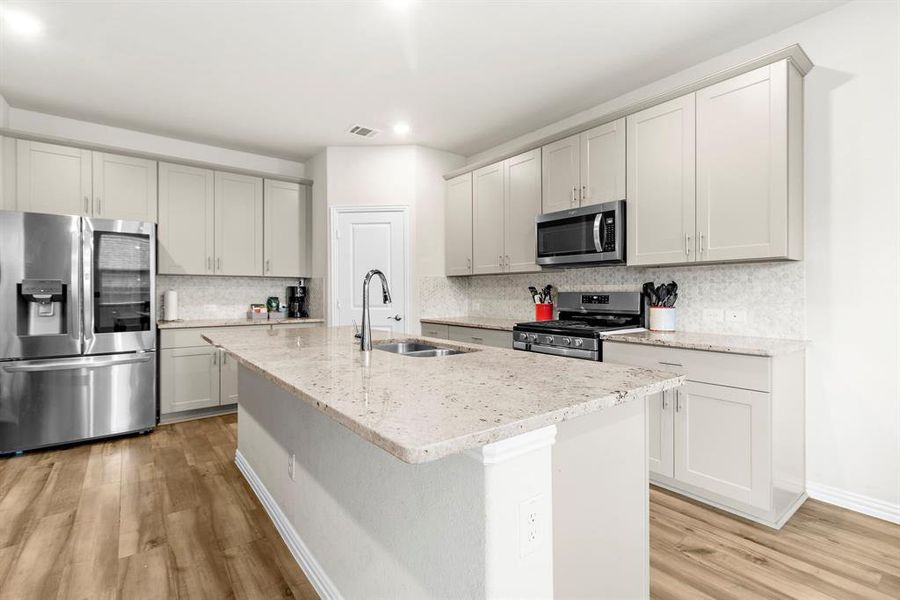 Kitchen featuring stainless steel appliances, light wood-style flooring, recessed lighting, backsplash, and a center island with sink Kitchen featuring stainless steel appliances, light wood-style flooring, recessed lighting, backsplash, and a center island with sink
