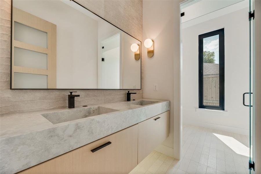 Bathroom featuring dual bowl vanity, backsplash, and tile patterned floors