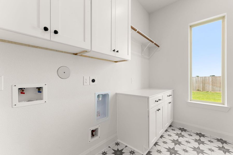The laundry room is finished with a bold black-and-white star-patterned tile floor and built-in upper cabinetry, along with a hanging rod for air-drying small details that make daily chores a little easier. The laundry room is finished with a bold black-and-white star-patterned tile floor and built-in upper cabinetry, along with a hanging rod for air-drying small details that make daily chores a little easier.