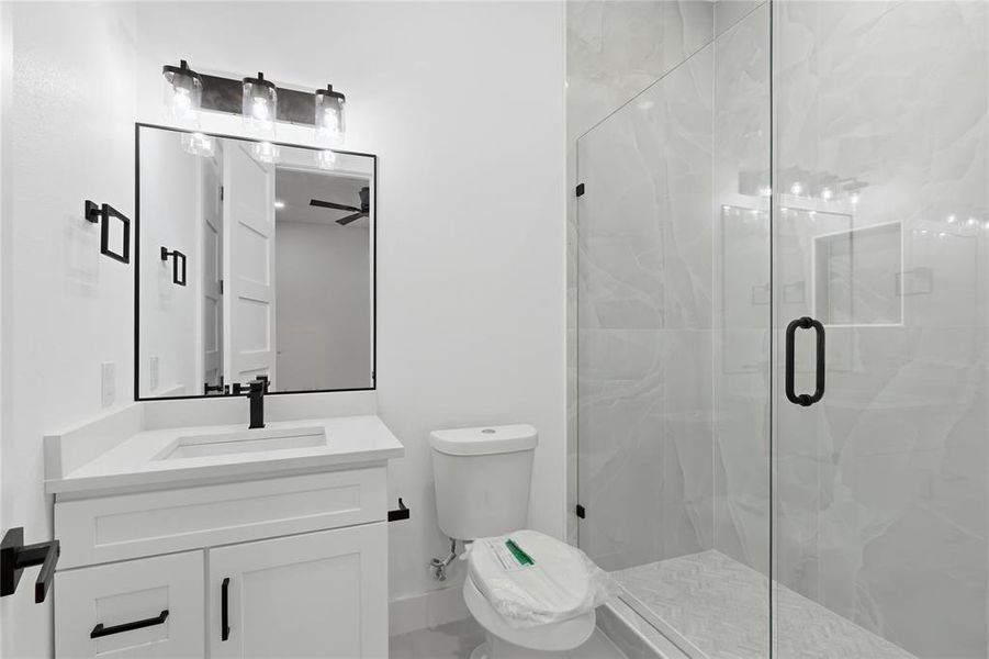 Bathroom featuring vanity and a marble finish shower