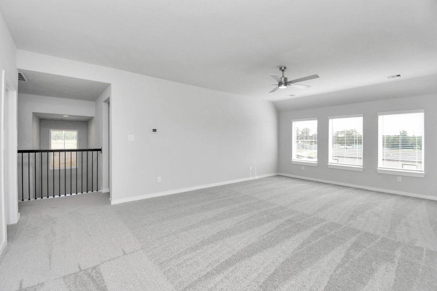 Come upstairs and relish a day of relaxation in this loft area! Ideal as an additional living space or game room, it boasts plush carpeting, high ceilings, custom paint, and windows that flood the area with abundant natural light. Sample photo of completed home with similar floor plan. Actual colors and selections may vary.