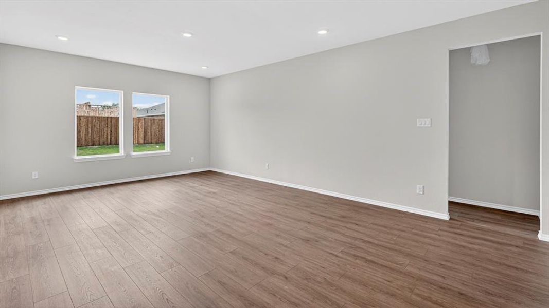 Expansive room with wood-finish flooring, recessed lighting, and two windows providing exterior light Expansive room with wood-finish flooring, recessed lighting, and two windows providing exterior light