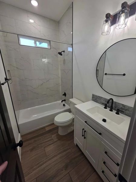 Bathroom featuring vanity, bathtub / shower combination, and dark wood-type flooring Bathroom featuring vanity, bathtub / shower combination, and dark wood-type flooring