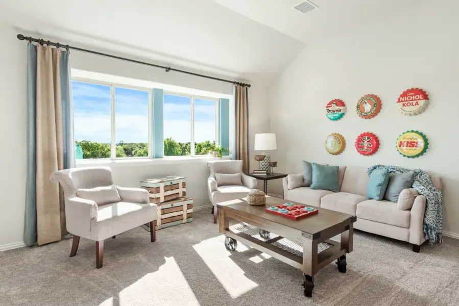 Casual living room with vaulted ceiling, neutral sofa, two armchairs, and vintage bottle cap wall decor