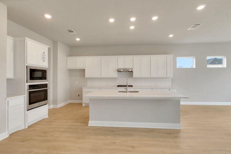 Kitchen featuring visible vents, a sink, light wood-style floors, black microwave, and stainless steel oven Kitchen featuring visible vents, a sink, light wood-style floors, black microwave, and stainless steel oven