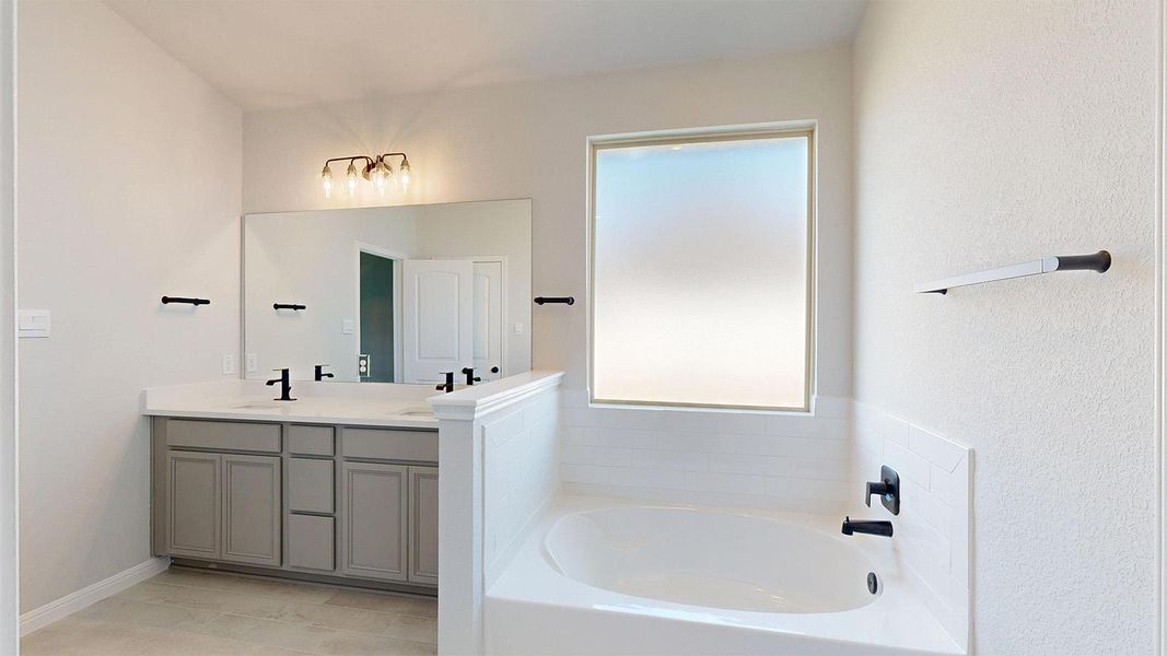 Full bath with double vanity, a bath, and light tile patterned floors Full bath with double vanity, a bath, and light tile patterned floors