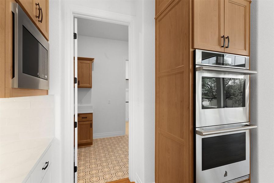 The kitchen features wood cabinetry, stainless steel appliances, and white countertops