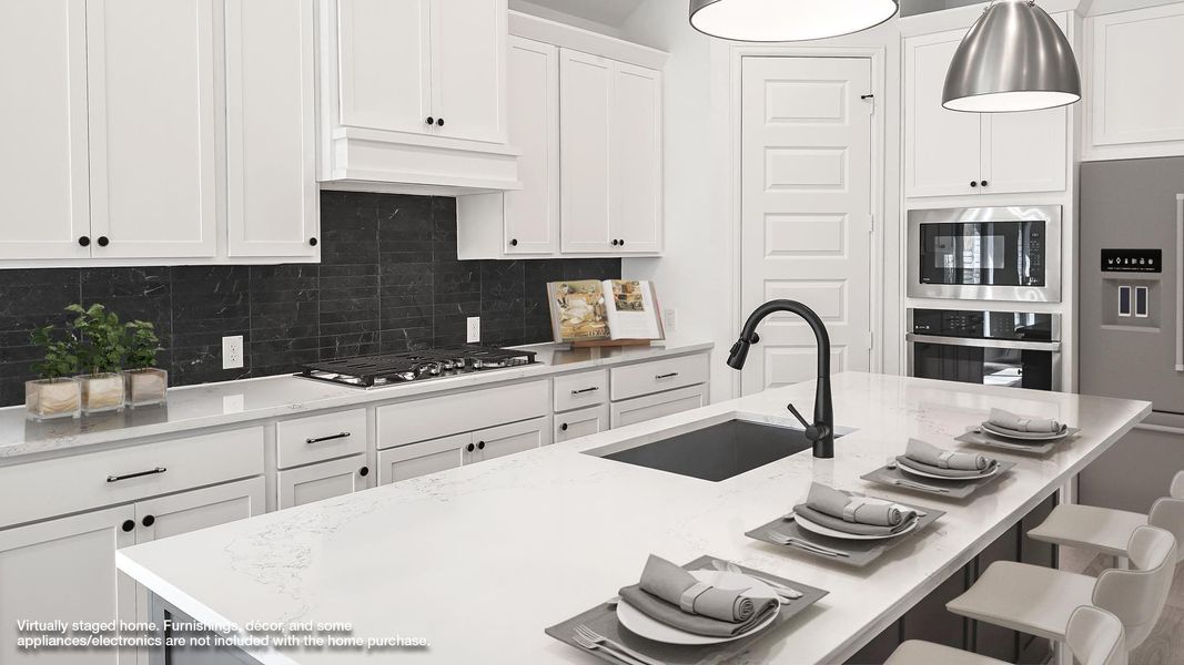 Kitchen featuring white cabinetry, appliances with stainless steel finishes, light stone counters, and a kitchen bar Kitchen featuring white cabinetry, appliances with stainless steel finishes, light stone counters, and a kitchen bar