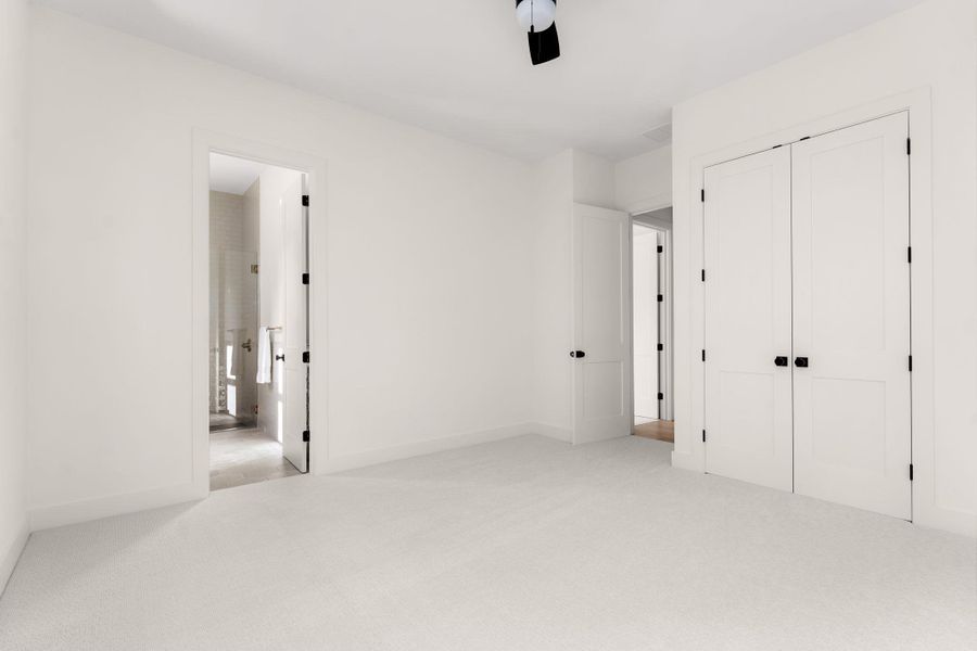 A spacious bedroom with plush carpeting provides serene comfort and direct bathroom access.