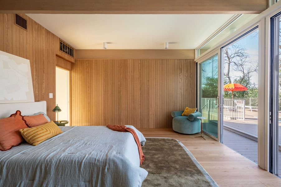 Bedroom featuring wood walls, access to exterior, and wood finished floors
