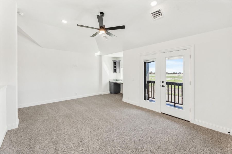 Open bonus room with carpet, ceiling fan, French doors to balcony, and small wet bar area Open bonus room with carpet, ceiling fan, French doors to balcony, and small wet bar area