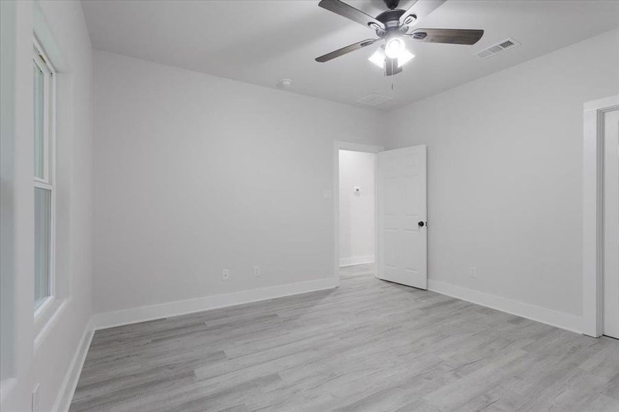 Empty room with light hardwood / wood-style floors and ceiling fan