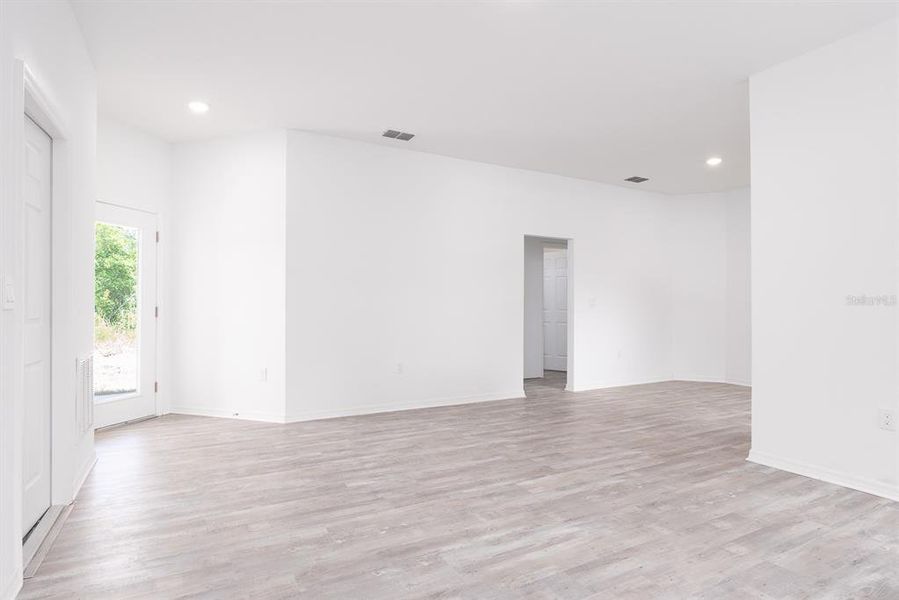 Great room area, garage door to the left, front door (clear), open doorway to all bedrooms, dining room to the upper right, and kitchen on the other side of the wall to the right.