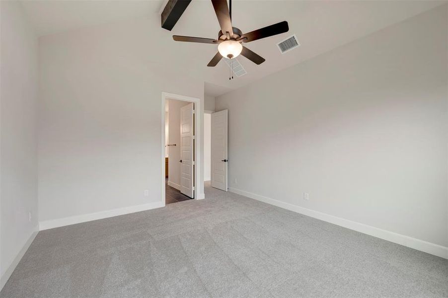 Unfurnished bedroom with light carpet, a ceiling fan, lofted ceiling, and connected bathroom