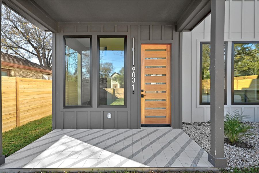 View of exterior entry featuring board and batten siding and fence