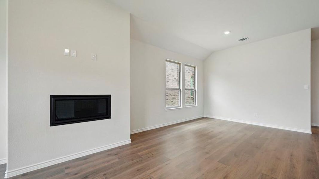Living area featuring an integrated fireplace, light wood-finish flooring, recessed lighting, and two windows