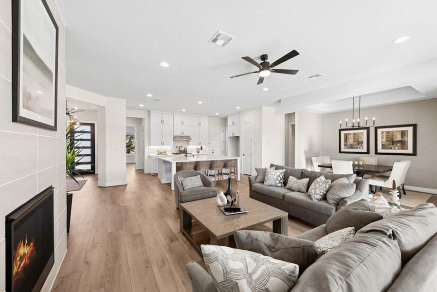 Living area featuring a tile fireplace, light wood finished floors, ceiling fan, recessed lighting, and a chandelier Living area featuring a tile fireplace, light wood finished floors, ceiling fan, recessed lighting, and a chandelier
