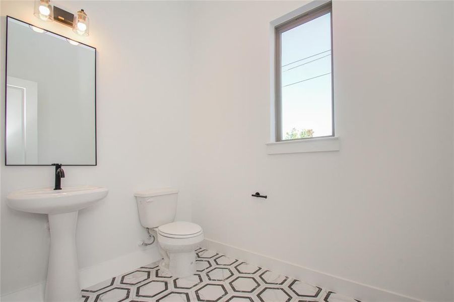 2nd floor large half bath with designer floor tiles and lighting. Photos of similar completed home by same builder. Selections may differ.