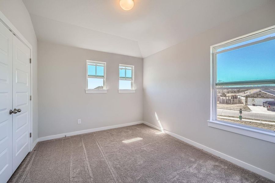 Unfurnished bedroom with lofted ceiling, carpet floors, and baseboards