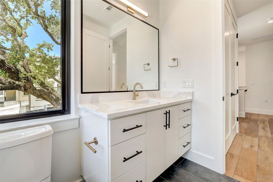 Bathroom featuring toilet, vanity, baseboards, and wood finished floors