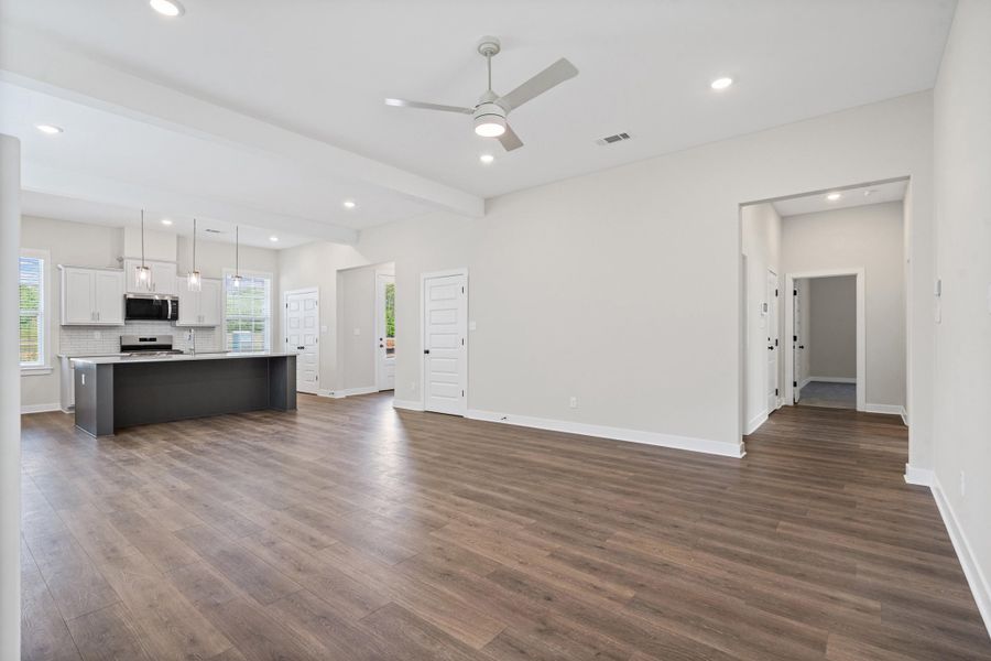 Unfurnished living room with a ceiling fan, dark wood-type flooring, beam ceiling, and recessed lighting Unfurnished living room with a ceiling fan, dark wood-type flooring, beam ceiling, and recessed lighting