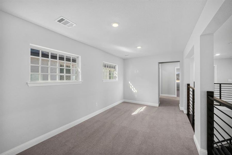 Carpeted loft space with recessed lighting and multiple windows