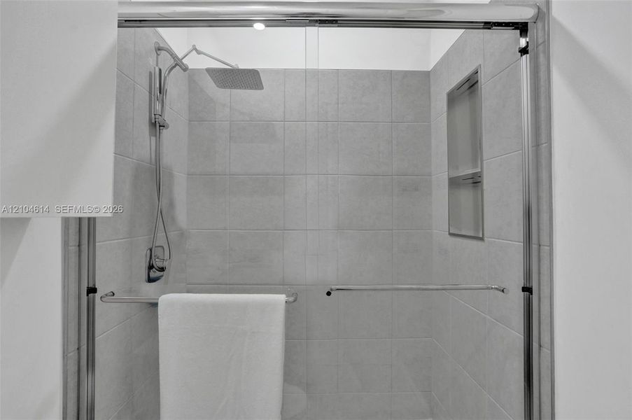 Frameless glass shower enclosure featuring a rectangular rain showerhead and a built-in shower niche
