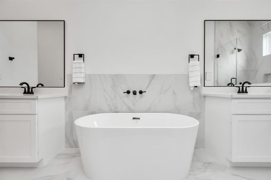 Indulge in relaxation with a spacious primary bath boasting a luxurious bathtub and double sinks with vanity and a large glass frame standing shower.