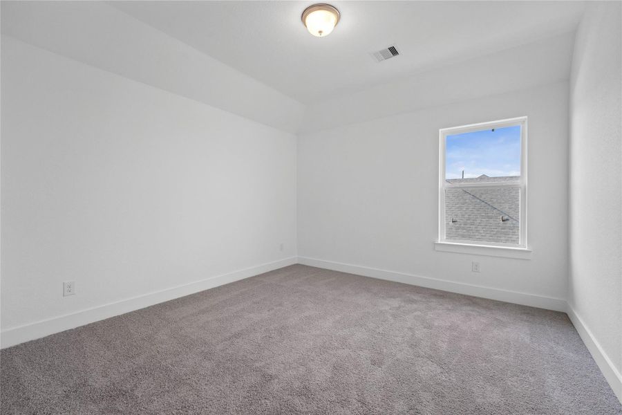 This inviting secondary bedroom combines comfort and modern elegance, featuring a soft neutral color palette, sleek design elements, and abundant natural light streaming through a large window.