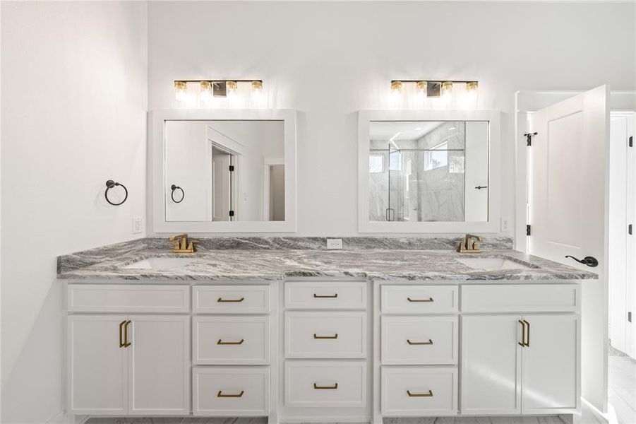 Full bath featuring double vanity and a marble finish shower