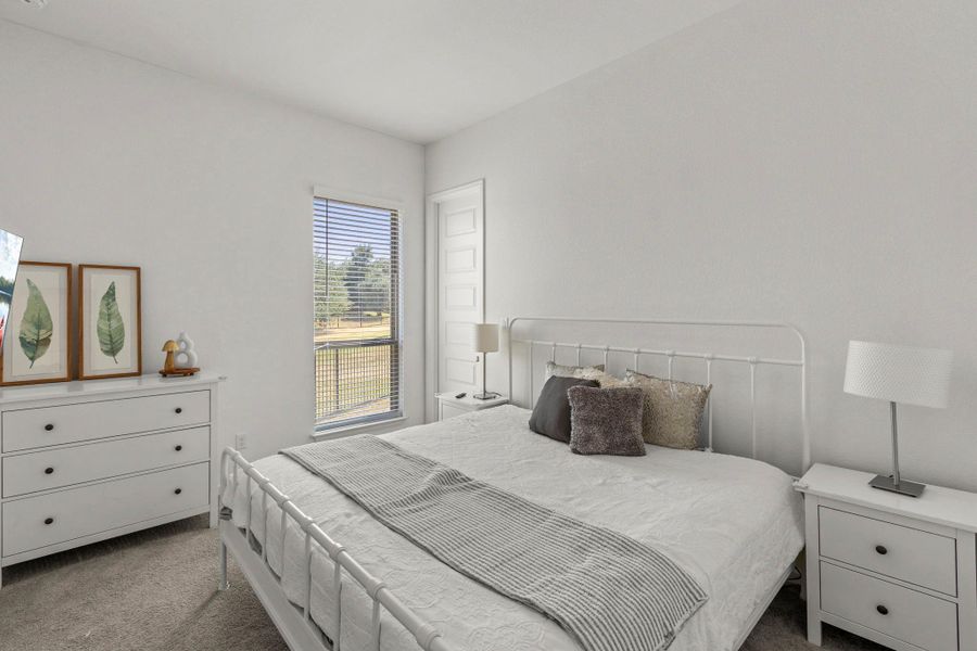 Plush carpeting and a large window framing scenic outdoor views anchor this tranquil bedroom.