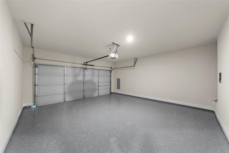 Garage with baseboards and electric panel