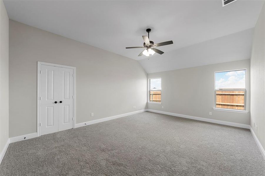Empty room with carpet floors, lofted ceiling, and a ceiling fan