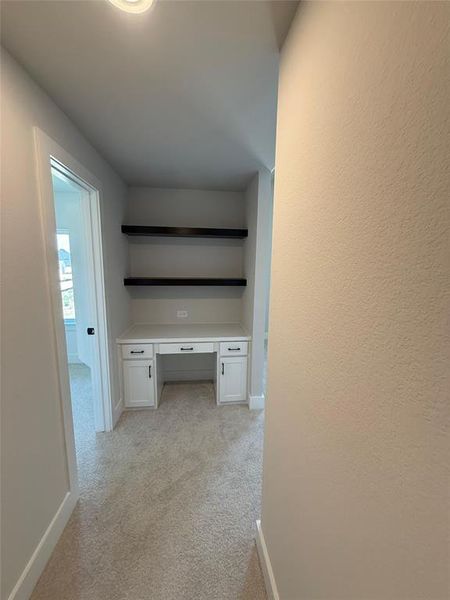 Hall with light colored carpet and a desk Hall with light colored carpet and a desk