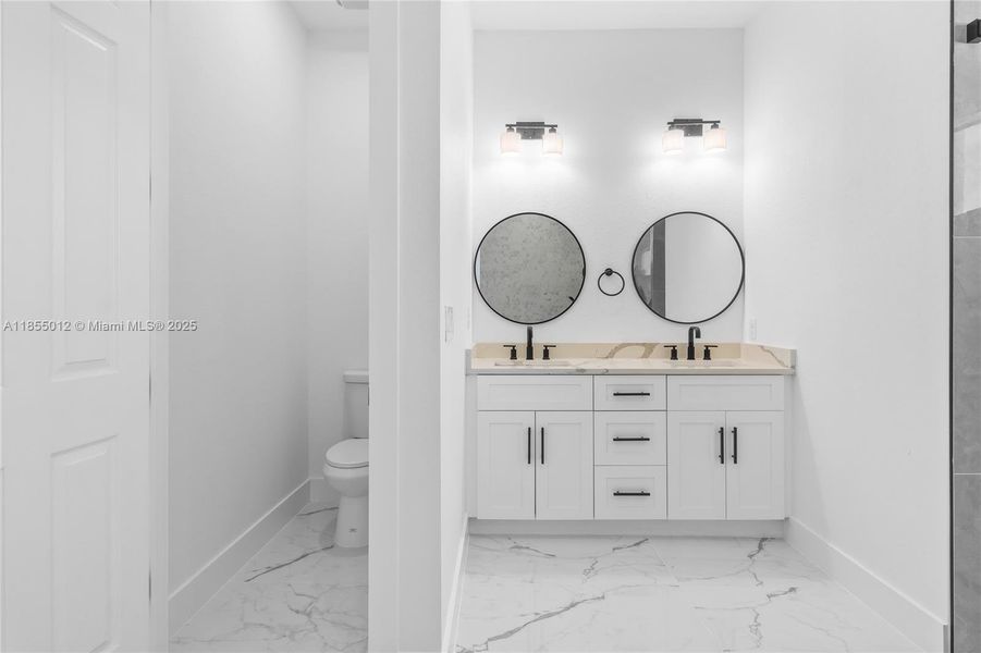 Bathroom featuring marble finish floor, baseboards, double vanity, and a sink