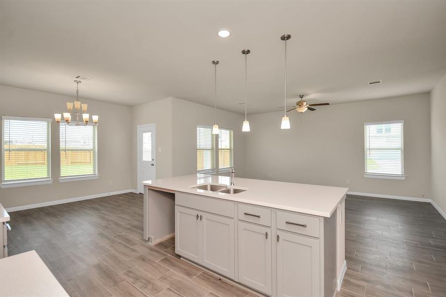 This kitchen is by far any chef’s dream! This spacious kitchen features large windows, high ceilings, wood cabinets, granite countertops, modern tile backsplash, recessed lighting with additional custom pendant lighting, extended counter space, granite kitchen island with sink and space for breakfast bar and a pantry all overlooking your huge living area. *This image is from another Saratoga Home with similar floor plan and finishes, not the Brittany floorplan.*