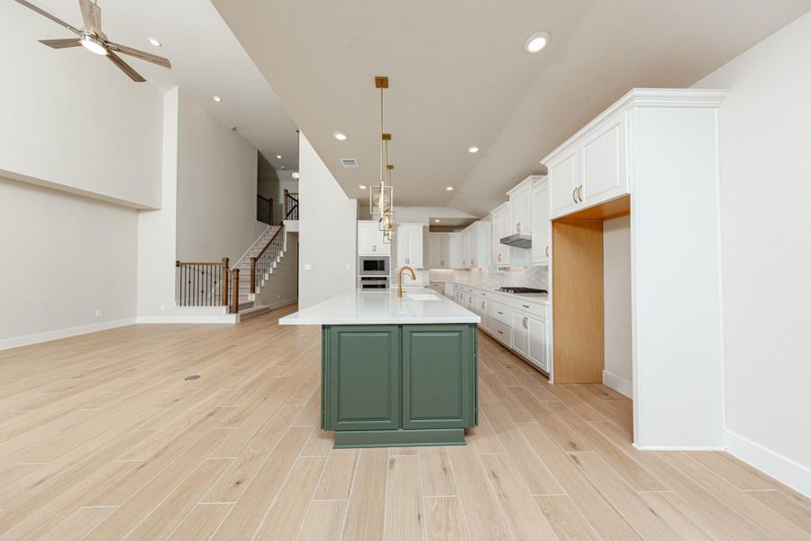 Three exquisite, brushed bronze globe shade pendants hang elegantly above the kitchen island, providing focused task lighting and a touch of refined style.