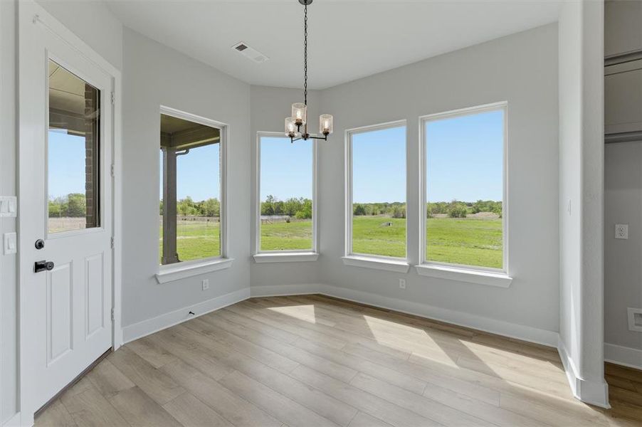 Unfurnished dining area featuring hanging lights and light wood-style flooring