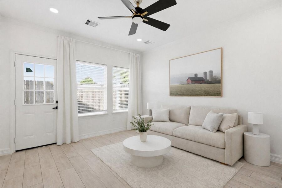 Spacious living room with ceiling fan, abundant natural light from large windows, and neutral finishes throughout.