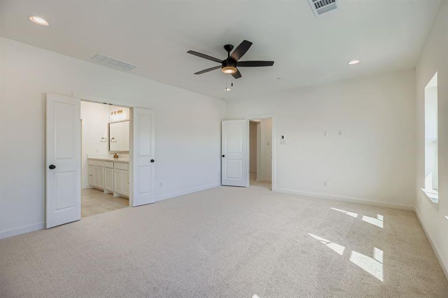 Unfurnished bedroom featuring recessed lighting, light colored carpet, ceiling fan, and ensuite bath Unfurnished bedroom featuring recessed lighting, light colored carpet, ceiling fan, and ensuite bath