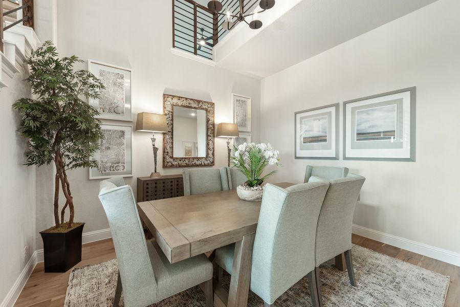 Dining room with wood table, six light blue chairs, high ceiling, and decorative mirror on the wall