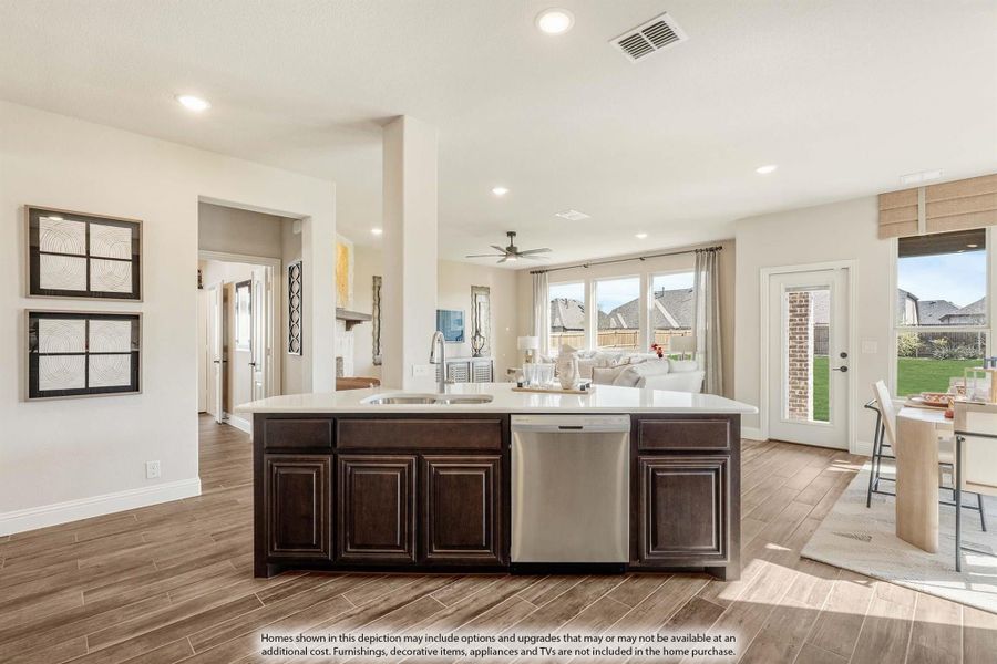 Open-concept kitchen with dark wood island, white countertop, and stainless steel dishwasher, overlooking living area with wood-look tile floors Open-concept kitchen with dark wood island, white countertop, and stainless steel dishwasher, overlooking living area with wood-look tile floors