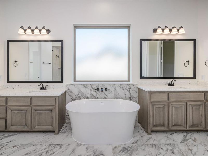 Bathroom featuring marble look tile flooring, healthy amount of natural light, and a freestanding bath Bathroom featuring marble look tile flooring, healthy amount of natural light, and a freestanding bath