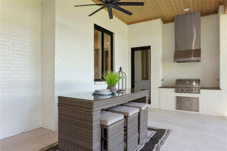 Backyard covered patio features built in grill with ventahood.