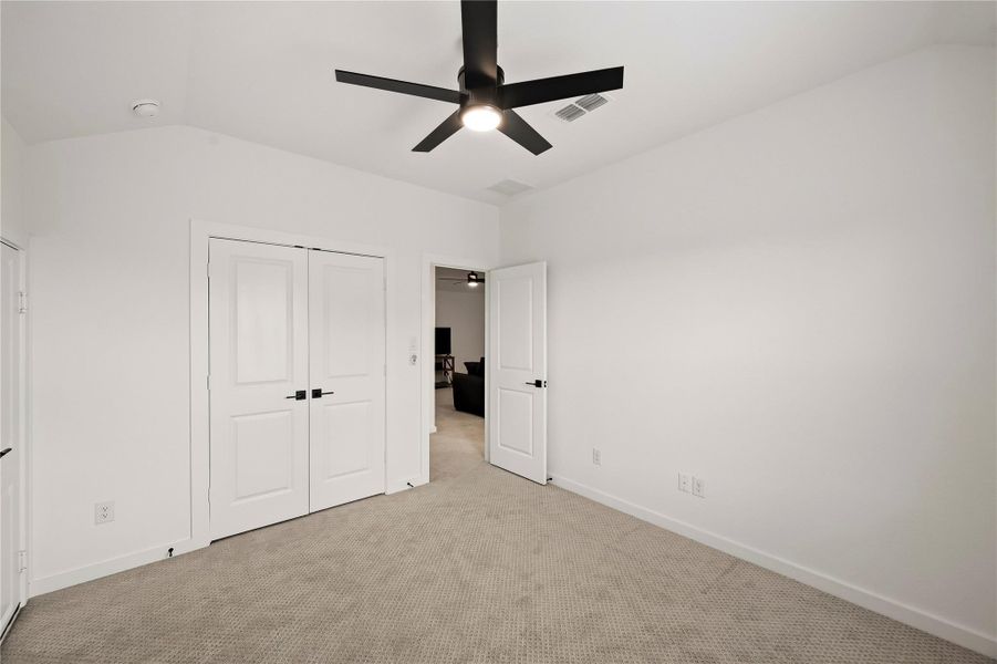 A ceiling fan with integrated lighting and a double-door closet enhance this well-appointed room. To the left, a separate door provides access to a dedicated storage area and attic access. A ceiling fan with integrated lighting and a double-door closet enhance this well-appointed room. To the left, a separate door provides access to a dedicated storage area and attic access.